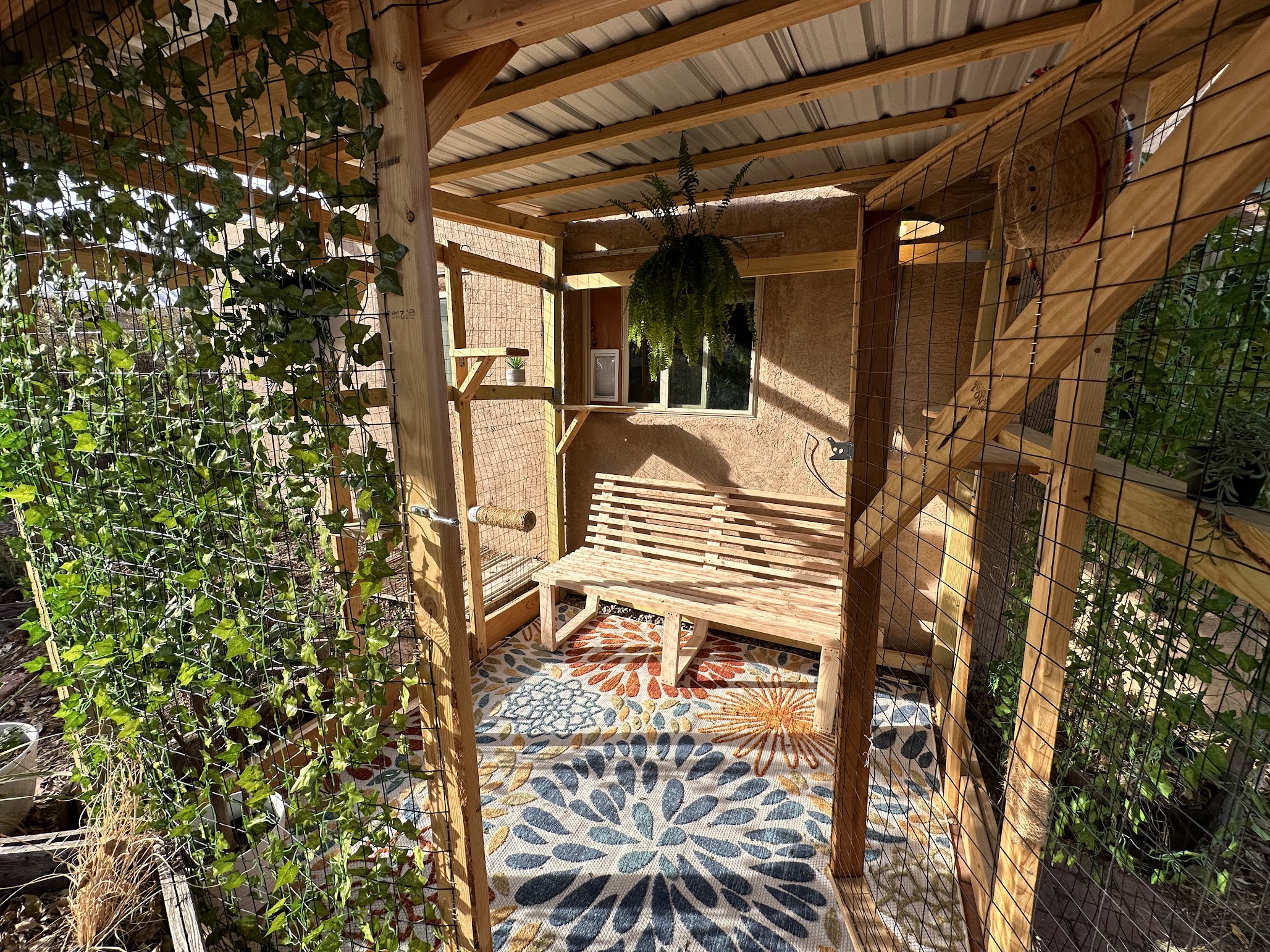Custom catio with wood framing, mosaic tile floor, and hanging plants